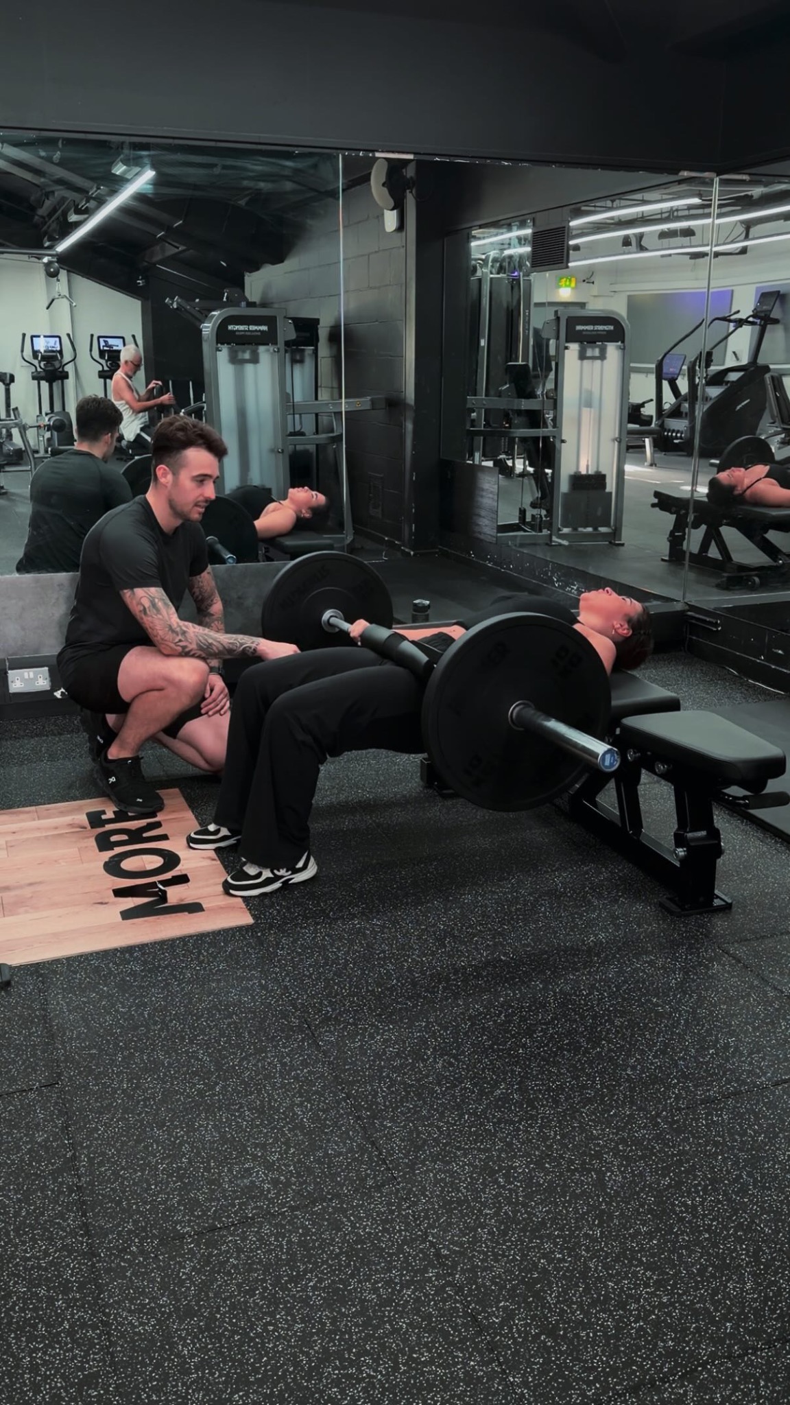 Joe Angelo coaching a client through a barbell hip thrust at Putlands Gym